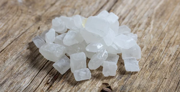 Кристаллы белого сахара на деревянной поверхности — стоковое фото