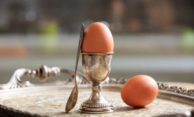 Eggs and egg cup in an old tray clipart