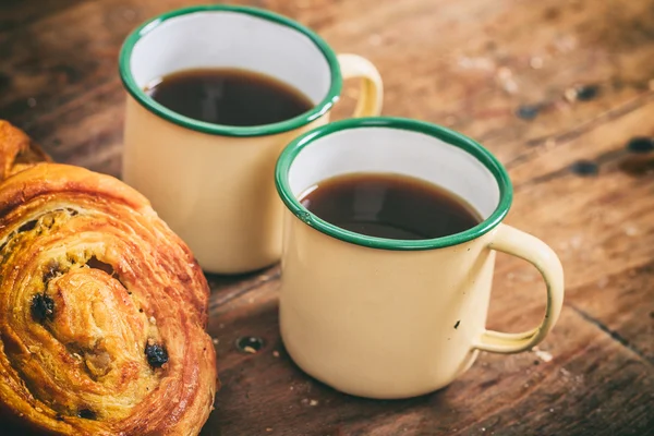 Cups of coffee and croissants on a wooden surface — Stock Photo, Image