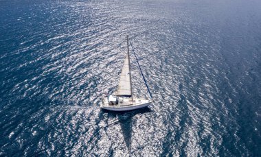 Yelkenli. Beyaz yelkenli yelkenli, dalgalı deniz arka planı. Ege Denizi Yunanistan 'da yaz tatili. Hava aracı görünümü