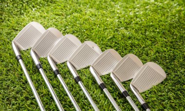 Golf sopaları yeşil sahada, güneş ışığı yansımaları, yakın görüş. Golf sporu ve kulüp konsepti.