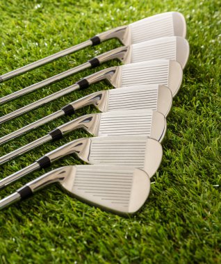 Golf sopaları yeşil sahada, güneş ışığı yansımaları, yakın görüş. Golf sporu ve kulüp konsepti.