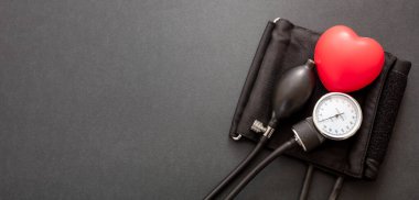Tansiyon ölçümü, hipertansiyon kontrolü. Tıbbi sphygmomanometre ve siyah arka planda kırmızı kalp, yakın çekim. Sağlık kardiyo denetimi kavramı.