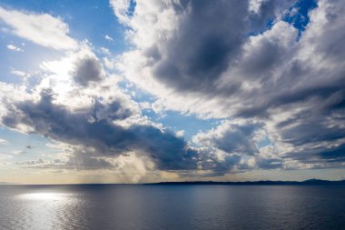 Deniz manzarası, Akdeniz 'de bulut manzarası. Ege Denizi 'nin üzerindeki bulutlar boyunca güneş ışığı suya yansıyor. Kea, Tzia Adası, Yunanistan.
