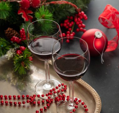 Noel kırmızı şarabı. Servis yapmaya hazır gümüş bir tepside iki şarap kadehi masada şenlikli Xmas süslemeleri, yakın çekim manzarası. Kış bayramı kutlaması