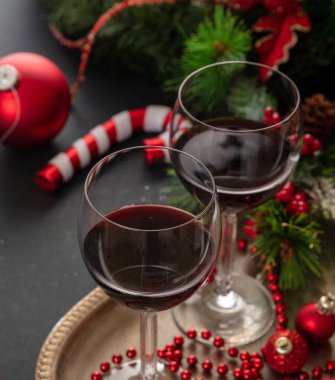 Noel kırmızı şarabı. Servis yapmaya hazır gümüş bir tepside iki şarap kadehi masada şenlikli Xmas süslemeleri, yakın çekim manzarası. Kış bayramı kutlaması