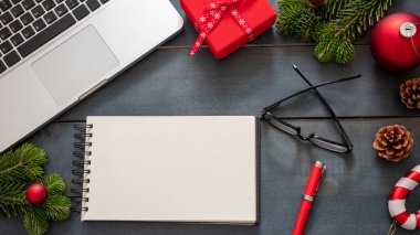 Noel, ofis kapalı. İş masası düzlüğü, tatil kartı şablonu. Mavi arkaplanda boş not defteri, dizüstü bilgisayar ve xmas dekorasyonu, üst görünüm, boşluk kopyala.