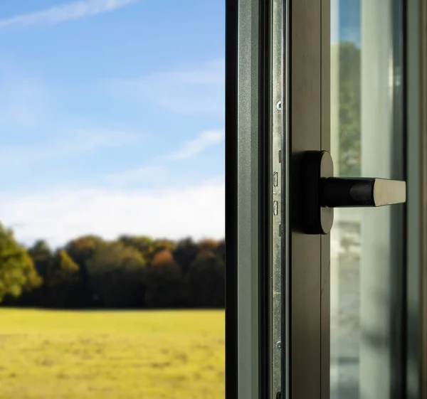 Aluminum door detail. Metal window frame open closeup view. Energy efficient, safety profile, blur outdoor nature background