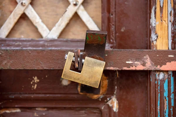 Heavy metal padlock with chain closeup on a brown color entrance gate. Safety, security concept