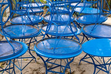 Kafe masaları yığını, kapalı işletme, Covid-19 Salgın Kapanması. Dışarıdaki mavi metal masalar, Monastiraki, Atina Yunanistan