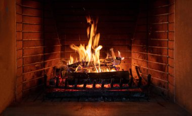 Fireplace, cozy warm fireside. Fire burning, logs flaming, firebricks background. Relaxation at home winter holiday christmas time clipart