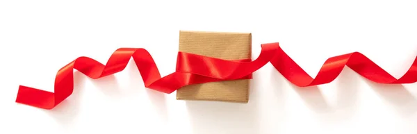 バレンタイン クリスマスプレゼント自家製包装 休日の準備 赤いサテンリボンで弓を作る 白い背景に隔離された茶色の紙のギフトボックスの装飾 — ストック写真