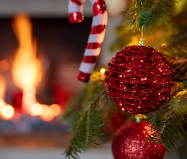 Noel ağacı, yanan şömine arka planı. Sıcak, rahat bir Noel tatili evi. Noel hediyesi, yakın plan, tebrik kartı şablonu