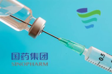 Atina, Yunanistan. 17 Aralık 2020. Mavi arka planda Çin aşısı logosu var. Covid19 aşı şişesi ve şırınga, Coronavirus aşı konsepti