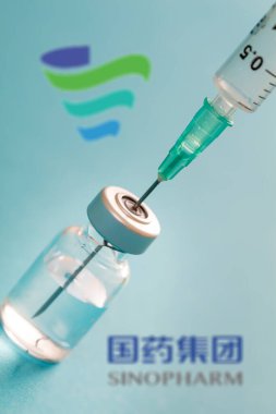 Atina, Yunanistan. 17 Aralık 2020. Mavi arka planda Çin aşısı logosu var. Covid19 aşı şişesi ve şırınga, Coronavirus aşı konsepti