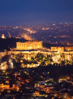 Akropolis ve Parthenon, Atina 'nın varış noktası. Geceleri aydınlanan kayaların havadan, dikey görüntüsü. Mermer sütunlarda ve tepede ışıkları olan antik anıt, sanat, kültür, medeniyet..