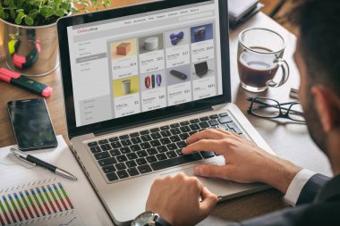 Çevrimiçi internet sitesi geliştiricisi, bilgisayarla çalışan adam, ekranda eshop web sayfası, ofis masası arka planı.
