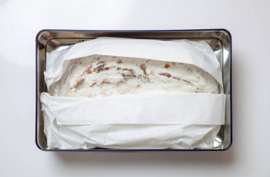 Noel pastası Christstollen beyaza izole edilmiş. Metal bir kutuda kağıt ile sarılmış geleneksel Alman ekmeği, üst manzara. Dresden 'den Xmas hediyesi