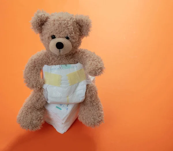 Baby Blöjor Och Söt Nalle Sitter Orange Färg Bakgrund Begreppet — Stockfoto