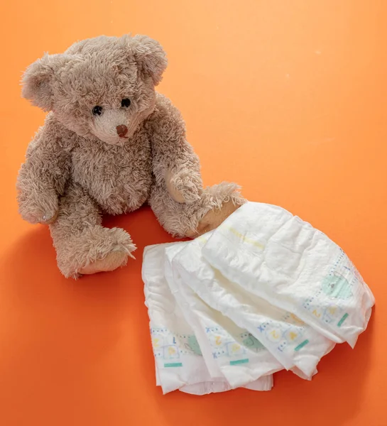 Baby Blöjor Och Söt Nalle Sitter Orange Färg Bakgrund Begreppet — Stockfoto