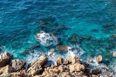 Deniz Burnu. Kayalıklarda dalgalar kırılıyor, yukarıdan kayalık kıyı manzarası, güneşli bir gün.