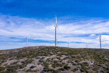 Tepede rüzgar türbinleri, rüzgar çiftliği, hava aracı manzarası. Yeşil ekolojik enerji üretimi. Alternatif enerji santrali, mavi bulutlu gökyüzü