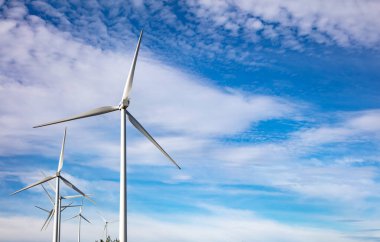 Mavi bulutlu arka planda rüzgar türbinleri, rüzgar çiftliği, hava aracı görüntüsü. Yeşil ekolojik enerji üretimi. Alternatif enerji santrali, boşluğu kopyala