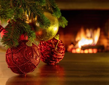 Xmas iç oda kutlama konsepti. Noel kırmızı parıltılı toplar ağaç dalında, yerde yansıma, yanan şömine arka planı, fotokopi alanı. Sıcak aile anları.