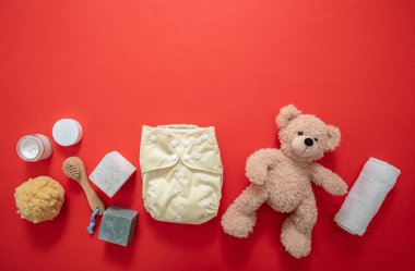 Bebek bakımı doğal ve sağlıklı ürünler. Bez bezi değiştirilmiş. Turuncu arka planda yenidoğan banyosu ve duş malzemeleri, üst manzara.