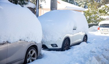 Kar fırtınası sorunları konsepti. Karla kaplı arabalar. Otomobiller park edilmiş, kış günü şehir sokağında mahsur kalmışlar. Karlı ağaçlar ve binalar. Donmuş araçların yakın görüntüsü.