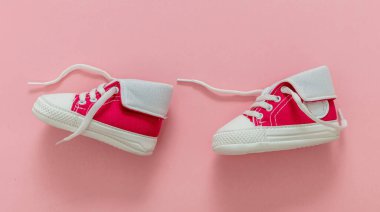 Bebek kız spor ayakkabıları pastel pembe arka planda yürüyor. Küçük beden ayakkabılar, tuval çizmeler. Kız ilk adımlar.