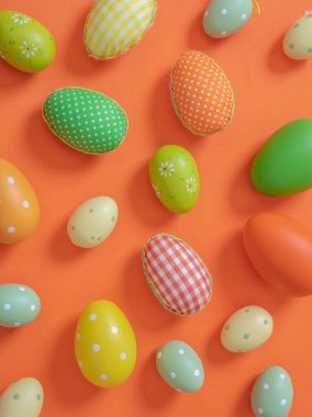 Easter eggs collection pastel green and orange colors on orange background, top view. Happy Easter greeting card. Christian religion holiday celebration and decoration.