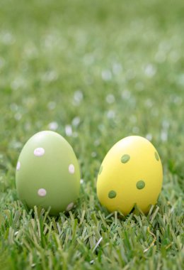 Happy Easter greeting card. Easter eggs hunt concept. Pastel colors eggs on green grass, outdoors in nature, closeup view. Christian religion holiday celebration and decoration.