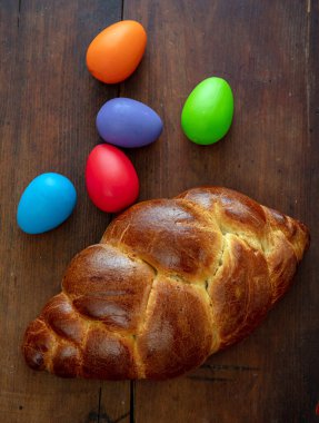 Paskalya yumurtaları ve tatlı ekmek, Yunan tsoureki cozonac somunu ahşap masa zemininde, üst manzara, şenlikli geleneksel din tatlısı, örülmüş brioche,