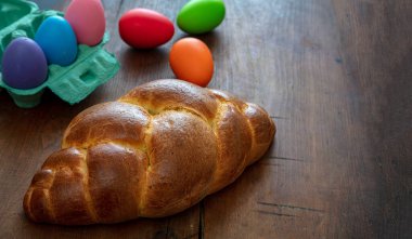 Tatlı ekmek ve renkli paskalya yumurtaları, ahşap masa arkasında tsoureki cozonac somun, Paskalya tebrik kartı şablonu. Geleneksel dini bayram tatlısı, örülmüş brioche