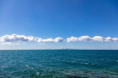 Mavi deniz ve gökyüzü arka planı. Deniz yüzeyinde açık gökyüzünde beyaz bulutlar, Ege Akdeniz, tatil beldesi Yunanistan.