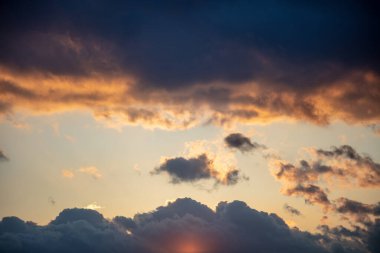 Renkli gün batımı ve karanlık bulutlu gökyüzü. Gündoğumu mavi turuncu turuncu renk cenneti, güneş ışınları ağır bulutların ardından arka plan, uzay. Güneş ışınlarının ufku boyadığı dramatik soyut sahne.