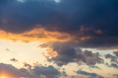 Güneş ışınları ağır bulut konseptinden geçiyor. Günbatımı mavi turuncu turuncu renk cenneti arka plan, uzay olarak. Renkli gün batımı ve karanlık bulutlu gökyüzü. Güneş ışınlarının ufku boyadığı dramatik soyut sahne.