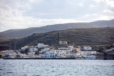 Yunanistan, Kythnos Adası, Cyclades. 15 Mayıs 2021. Loutra marinasına denizden yaklaşıyoruz. Rocky manzarası, Kiklad geleneksel mimarisi, yat limanında yelkenli. Sakin deniz, mavi gökyüzü