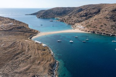 Yunanistan, Kythnos Adası, Cyclades. Kolona çift taraflı kumlu plaj, hava aracı manzaralı. Yelkenliler kıyıdan açıkta, dalgalı deniz, mavi gökyüzü arka planı. Yaz tatili ve Ege Denizi 'nde yelkencilik
