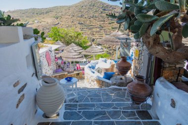 Yunanistan, Sifnos Adası. 19 Mayıs 2021. Kastro köyünde taş döşeli merdivenlerde açık dükkan ve kafe, geleneksel Yunan sikladik adaları mimarisi, güneşli bir gün.