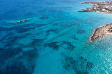 Yunanistan. Küçük Cyclades deniz manzarası. Beyazlatılmış binalar, kayalık kıyı şeridi ve dalgalı yeşil zümrüt rengi açık deniz suyu, Koufonisi adası, hava aracı manzarası. Ege Denizi yaz tatili