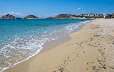 Kumsal arka planı, kumdaki yumuşak okyanus dalgası. Boş plaj, boşluk, yaz tatili kartı ve reklam şablonu. Açık mavi gökyüzü, sakin deniz arka planı. Mykonos Adası, Cyclades. Yunanistan