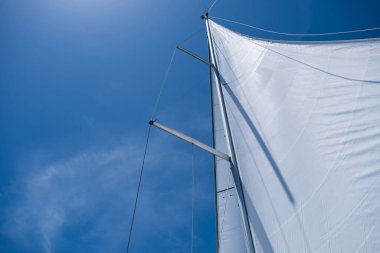 Yacht open sails on clear blue sky background. Sailing with the wind at Aegean sea, summer holidays at Greek islands. Looking up at the sky, low angle view