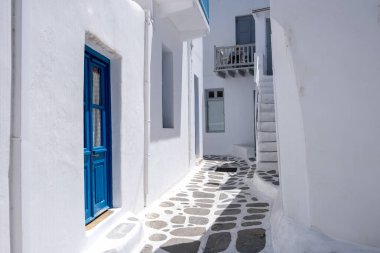 Mykonos island, Greece. Whitewashed buildings, narrow cobblestone street. Chora village traditional architecture in white and blue colors. Summer vacations destination, Cyclades