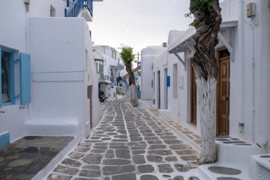 Whitewashed buildings, narrow cobblestone street. Mykonos island, Cyclades Greece. Chora village traditional architecture in white and blue colors. Summer vacations destination,