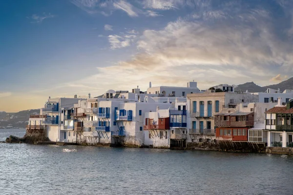 Mykonos island Little Venice at sunrise. Aegean Sea. Cyclades Greece. Waterfront traditional buildings with colorful windows and balconies over the rippled sea, cloudy blue sky background