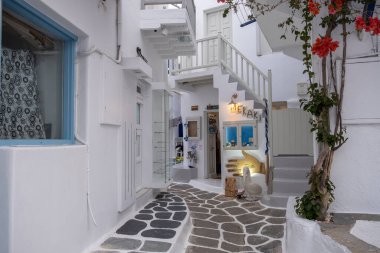 Mykonos island, Cyclades, Greece. May 20, 2021. Chora streets. Gifts shop Greek art, empty narrow cobblestone alley, whitewashed houses, blue windows doors. Summer cosmopolitan touristic destination.