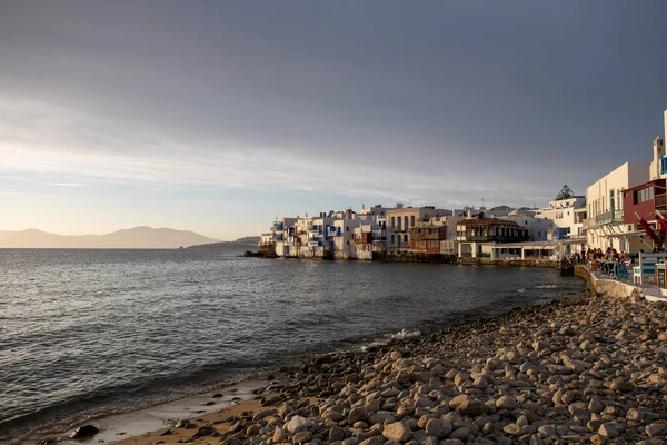 Mykonos island, Cyclades, Greece. May 20, 2021. Little Venice landmark, famous cosmopolitan destination. Traditional houses with balconies over the sea. Cafe restaurants at the seaside at sunset