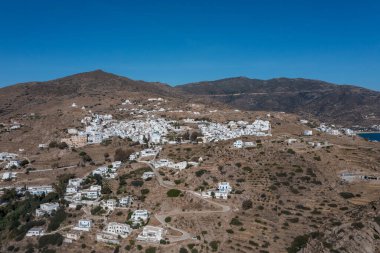 Ios Cyclades adaları, Yunanistan. Chora kasabasının insansız hava aracı görüntüsü. Geleneksel Kiklad mimarisi, kayalık arazide beyazlatılmış binalar, mavi gökyüzü arka planı. Yaz tatilleri